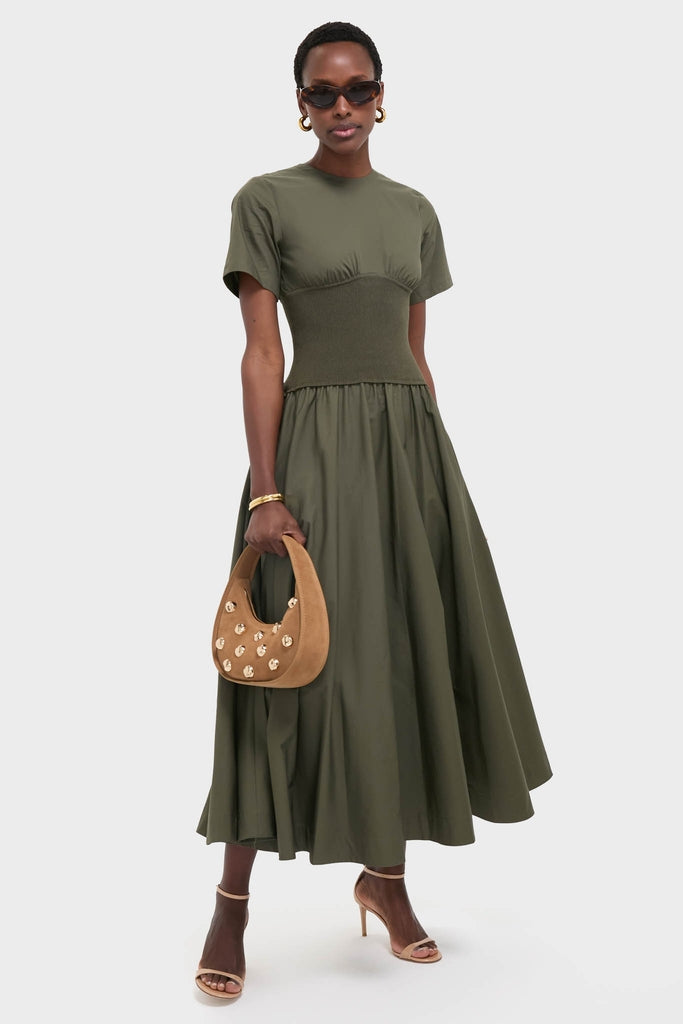 Woman models the Fern Wrenna Short Sleeve Midi Dress, an olive-green classic with a flared skirt, styled effortlessly with chic accessories for a fun, high-end look.