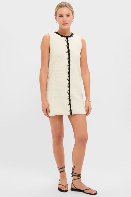 White Knit Lalia Mini Dress: A classic, effortless crochet mini with black scalloped trim and gold buttons, styled with flat sandals for a fun, high-end look.
