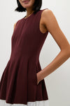 Person wearing the Mahogany Multi Raleigh Midi Dress, featuring a classic sleeveless fit-and-flare design with seamless burgundy top, pleated skirt, and effortless white hem detail.