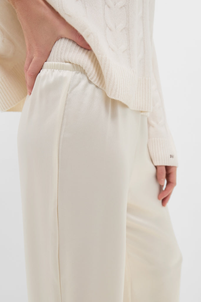 Model wearing classic Creme Barb Wide Leg Pants with a cable-knit sweater, showcasing their effortless, high-end style. Features include a relaxed fit and elastic waistband for everyday elegance.