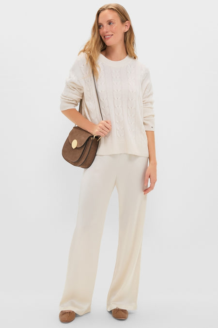 Woman models classic Creme Barb Wide Leg Pants, featuring a relaxed, high-end fit, styled effortlessly with a cable-knit sweater and suede cross-body bag. Perfect for a fun, everyday look.