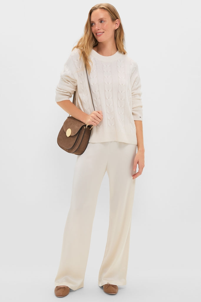 Woman models classic Creme Barb Wide Leg Pants, featuring a relaxed, high-end fit, styled effortlessly with a cable-knit sweater and suede cross-body bag. Perfect for a fun, everyday look.