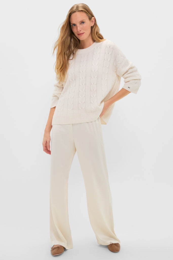 Woman models Creme Barb Wide Leg Pants with a classic, effortless style, featuring a relaxed fit and elastic waistband, paired with a cable-knit sweater and ballet flats.