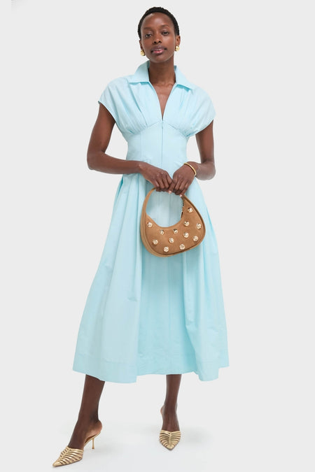Woman in an aqua-blue dress holds the classic Camel Finn Studded Suede Shoulder Bag, effortlessly styled with gold accents for a fun, high-end look.