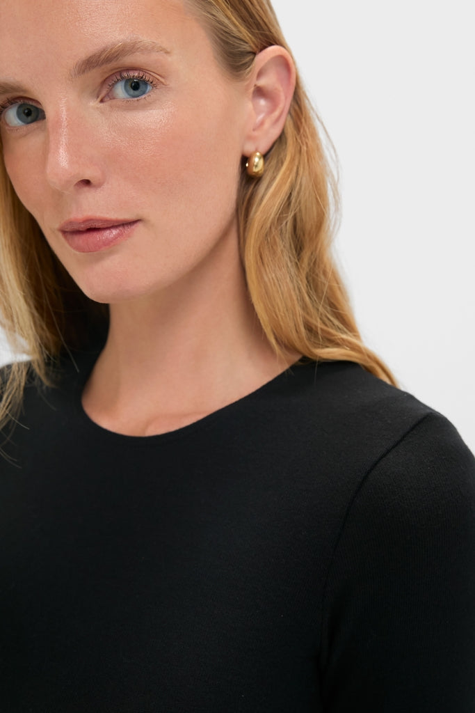 Person wearing a classic Black Lauren Mid Sleeve Tee, showcasing its crewneck and fitted elbow-length sleeves, embodying an effortless and high-end style.