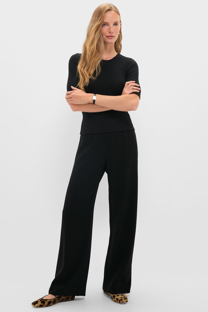 Woman in black Lauren Mid Sleeve Tee and wide-leg trousers, exuding a classic, effortless style with leopard flats. Perfect for fun, high-end versatility.