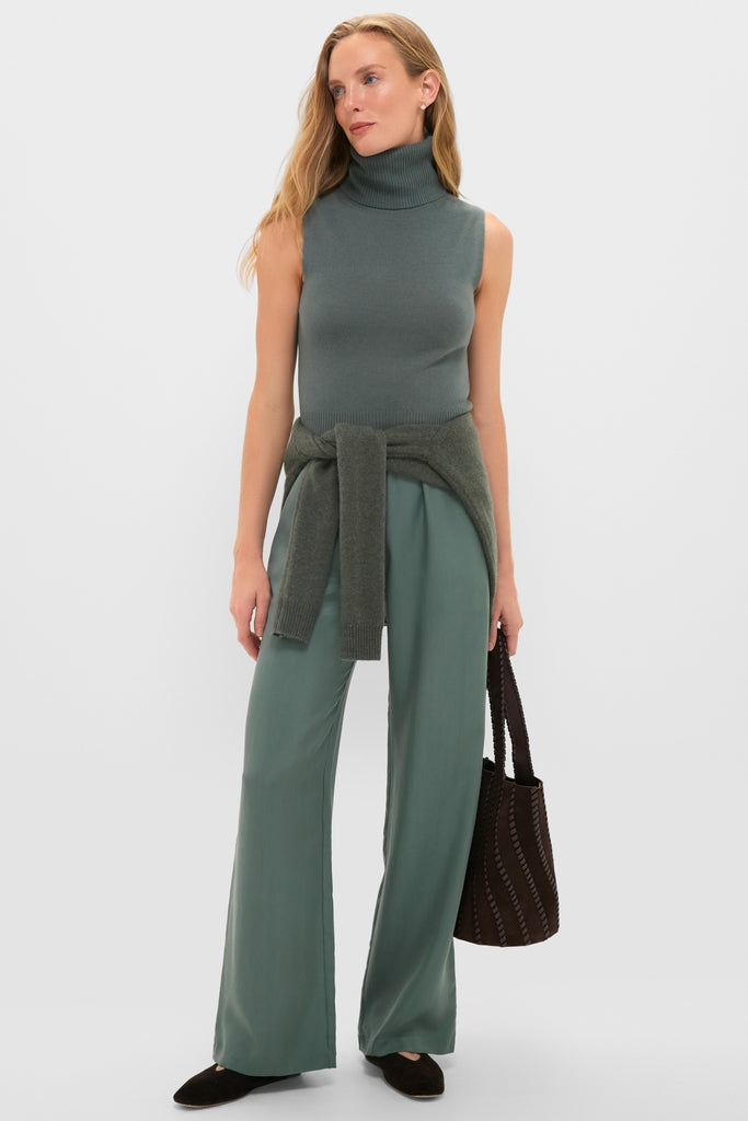 Model wearing Eucalyptus Kim Pocket Pants, a classic and effortless high-waisted, wide-leg style, paired with a sleeveless turtleneck and dark woven tote for a fun, high-end look.