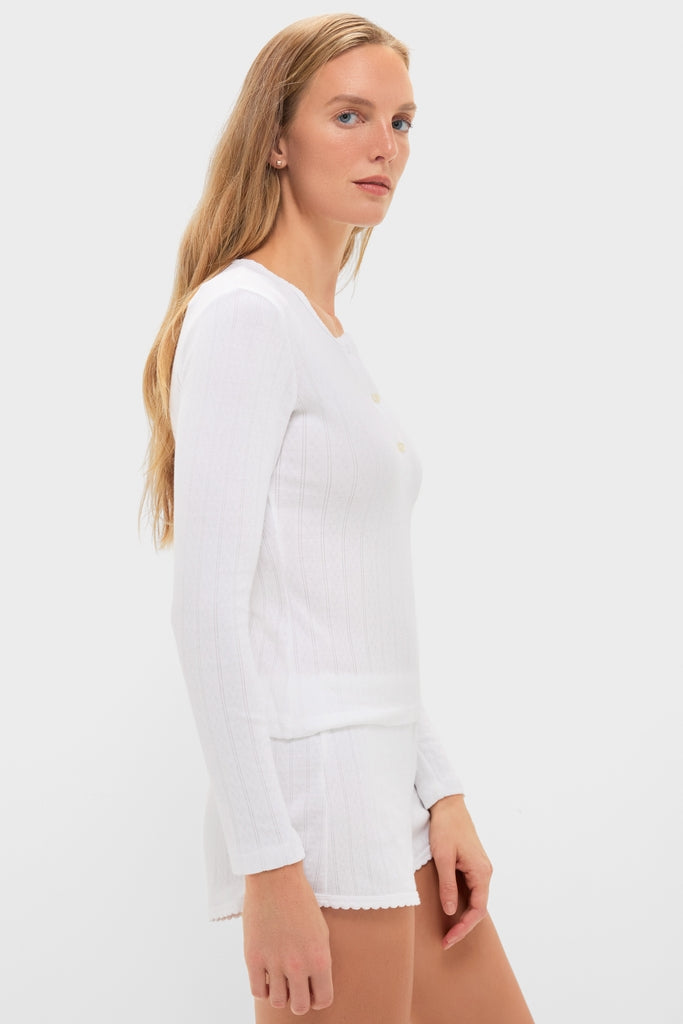 Side-profile of a young woman in a classic, effortless White Pointelle Long Sleeve Henley Tee, paired with matching shorts, embodying high-end, fun fashion.