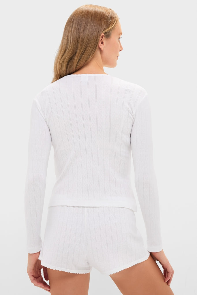 Woman in classic, effortless White Pointelle Long Sleeve Henley Tee with ribbed shorts, highlighting a fun, high-end loungewear look.