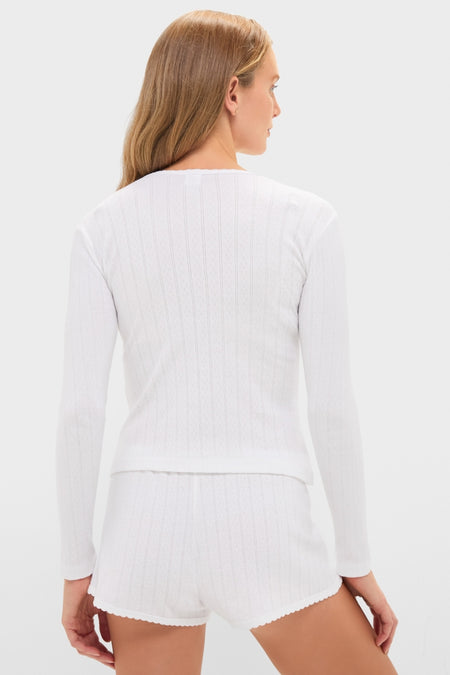 Woman in classic, effortless White Pointelle Long Sleeve Henley Tee with ribbed shorts, highlighting a fun, high-end loungewear look.