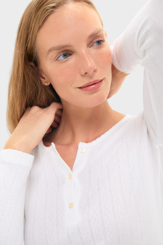 Young woman models a classic White Pointelle Long Sleeve Henley Tee, exuding effortless elegance with its rib-knit texture and fun, high-end style.