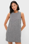 Young woman wearing the classic Black and White Gingham Mini Dress, showcasing an effortless, high-end look with a shift silhouette and side pockets.