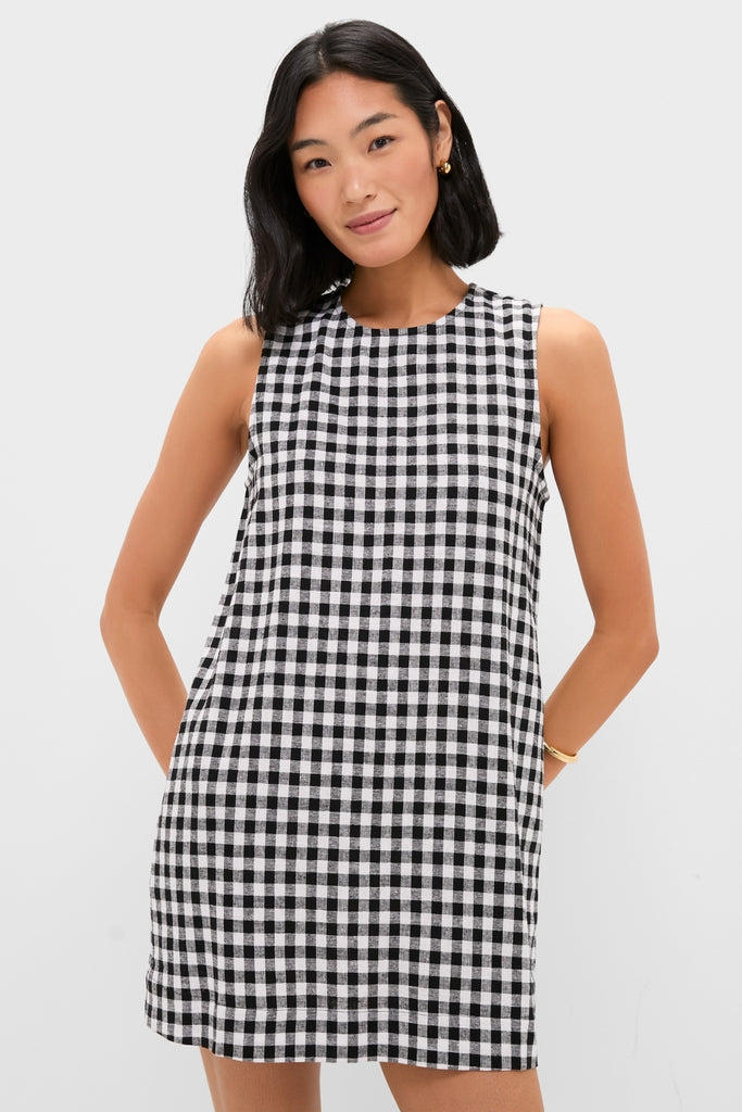 Young woman wearing the classic Black and White Gingham Mini Dress, showcasing an effortless, high-end look with a shift silhouette and side pockets.