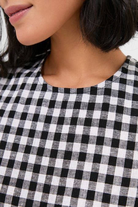 Close-up of a person wearing the Black and White Gingham Mini Dress, showcasing its classic, effortless style with a shift silhouette and round neckline.