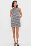 Woman modeling the Black and White Gingham Mini Dress, a classic, effortless shift style with side pockets, embodying fun and high-end fashion with black strappy sandals.