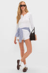 Woman in a classic, effortless ensemble featuring high-end White Pointelle Boxer Shorts, with a fun blue-and-white striped shirt tied at the waist, epitomizing Tuckernuck's chic style.