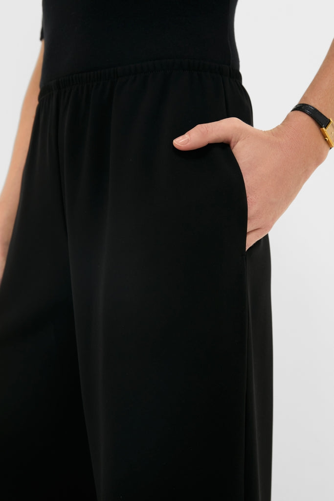 Person wearing Black Arielle Pocket Pants with elastic waistband and side pockets, paired with a black top and classic wristwatch for an effortless, high-end look.