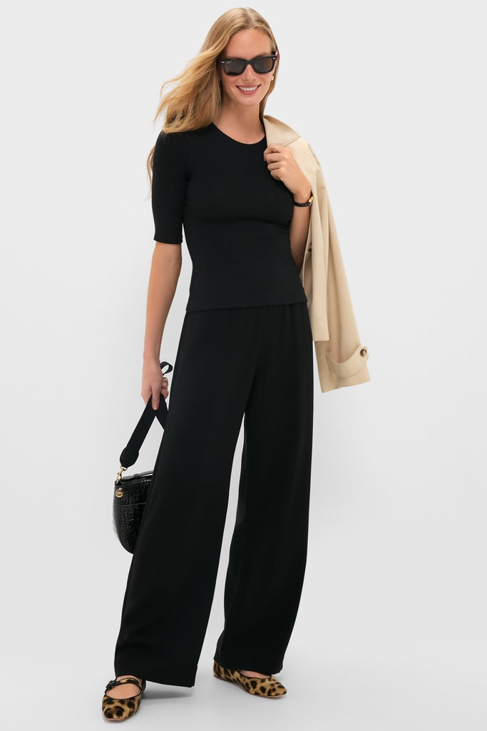 Woman in Black Arielle Pocket Pants, styled with leopard flats and a beige trench, embodies an effortless, high-end look with classic accessories and a fun, relaxed silhouette.