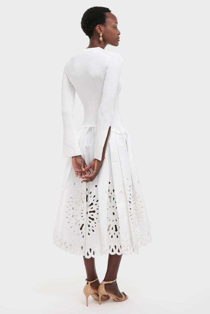 White Daila Midi Dress: A classic, effortless look with a ribbed sweater top, eyelet cotton skirt, scalloped hem, and chunky gold-tone earrings, perfect for a high-end, fun occasion.