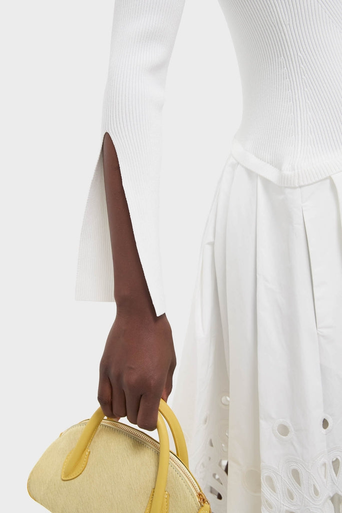 White Daila Midi Dress showcases classic elegance with slit sleeves and an eyelet-embroidered skirt, paired with a fun, structured yellow handbag for an effortless, high-end look.