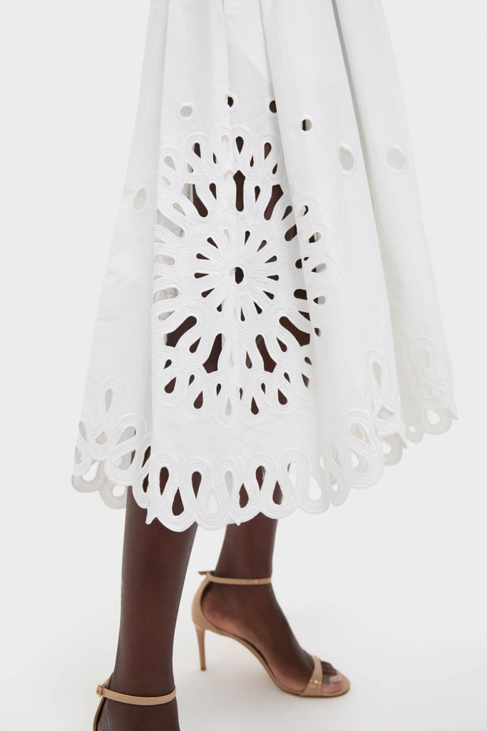 White Daila Midi Dress with scalloped, floral-mandala eyelet hem, paired with nude stiletto sandals. Classic, effortless style for any fun, high-end occasion.