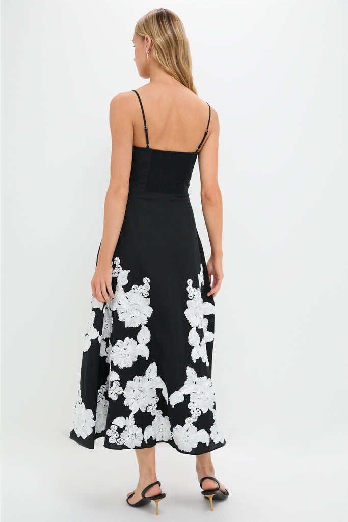 Woman in Black Multi Annabella Midi Dress with floral appliqués, showcasing a classic, effortless style with adjustable straps and slingback sandals; perfect for a high-end, fun look.