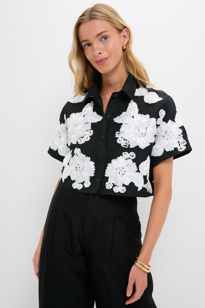 Model wearing Black Multi Callie Camp Shirt with oversized white floral details, paired with high-waisted black trousers. An effortlessly cool, high-end, and classic look.