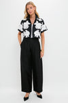 Model wearing the Black Multi Callie Camp Shirt with white floral appliqués, styled with high-waisted trousers and gold accessories. A classic, effortless high-end look.