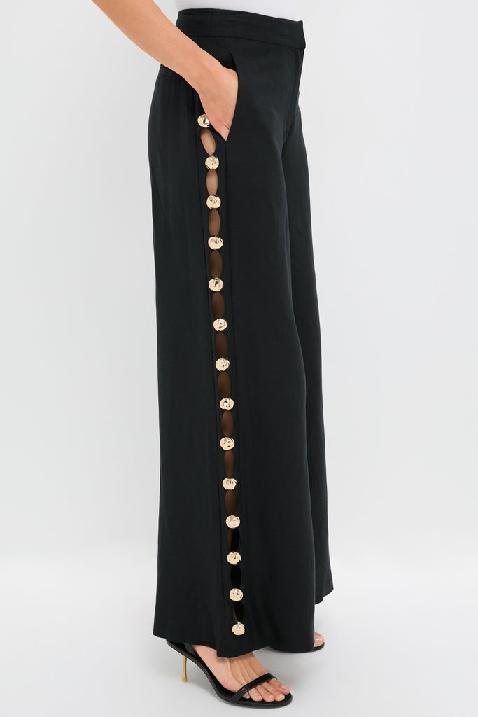 Woman wearing Black Cayman Wide Leg Pants with gold-tone disc detailing, exuding classic, effortless style; paired with black strappy heels for a fun, high-end look.