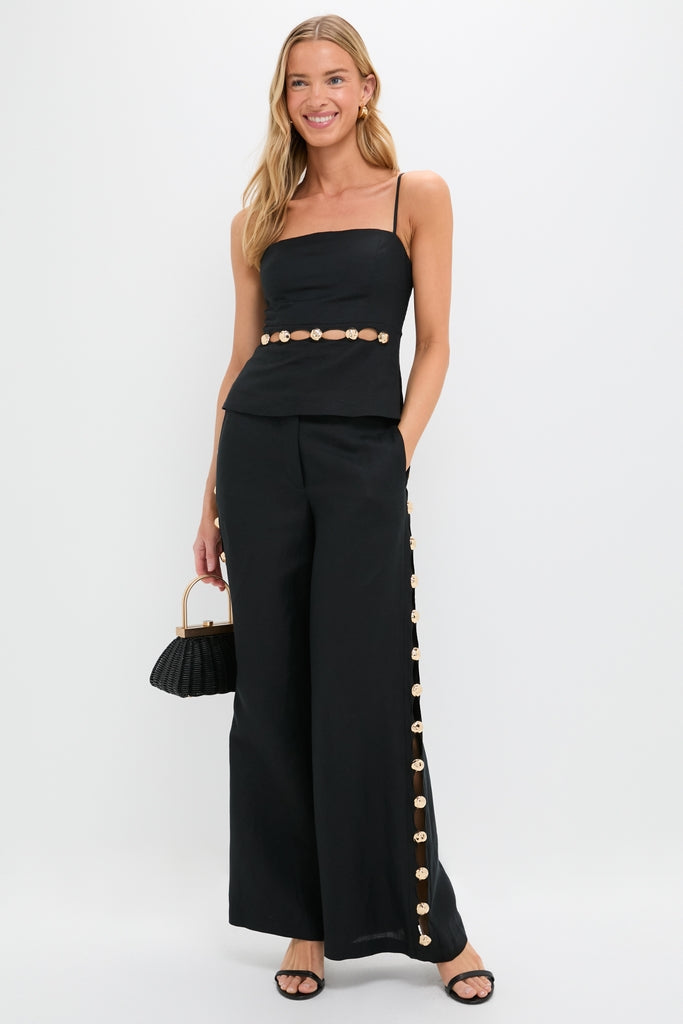Young woman wearing classic Black Cayman Wide Leg Pants with gold-tone embellishments, embodying effortless style. Paired with a matching top, exuding high-end, fun sophistication.