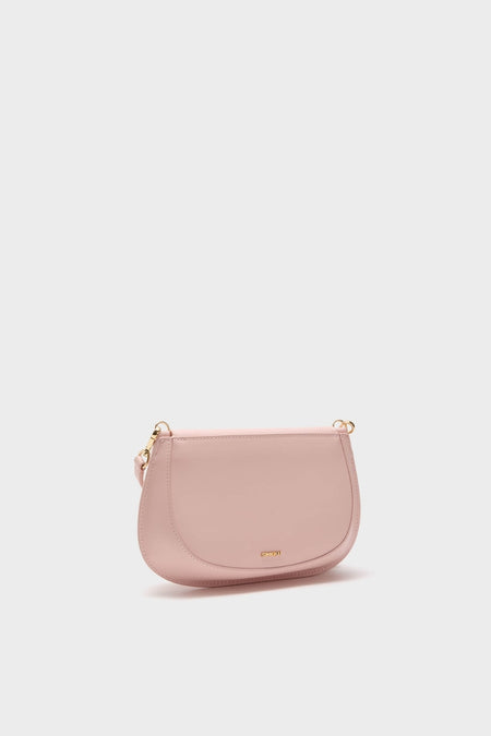 Pale Pink Logan Leather Crossbody: A classic, high-end saddle-shaped bag with an effortless blush-pink finish, gold-tone hardware, and adjustable strap for fun, stylish wear.