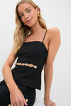 Young woman models the Black Cruz Cami, featuring waist cutouts and gold hardware, embodying classic and effortless high-end style. Perfectly paired with matching bottoms for a fun, polished look.
