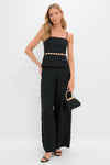 Woman in Black Cruz Cami with gold embellishments, paired with high-waisted trousers and open-toe heels, exuding an effortless, high-end, and classic style.