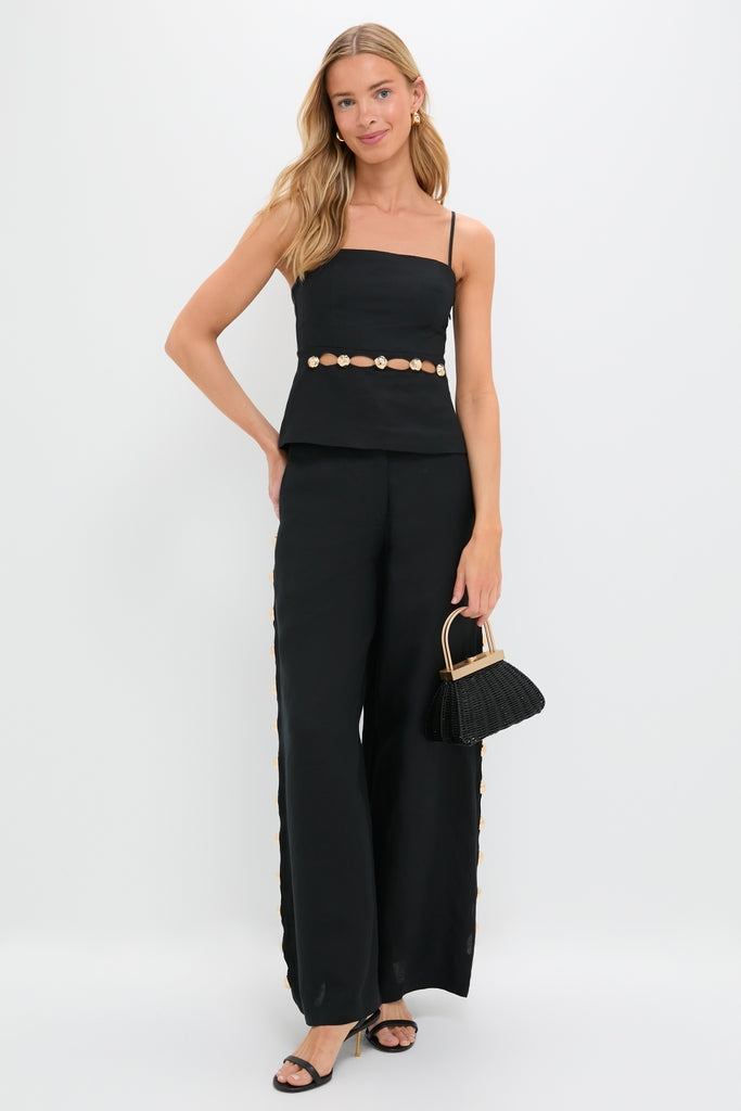 Woman in Black Cruz Cami with gold embellishments, paired with high-waisted trousers and open-toe heels, exuding an effortless, high-end, and classic style.