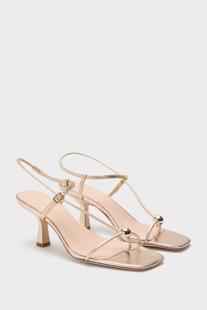 Champagne Metallic Triana Heels with slim straps, T-bar, gold ball detail, and adjustable slingback, offering a classic, effortless, and fun high-end style for versatile occasions.