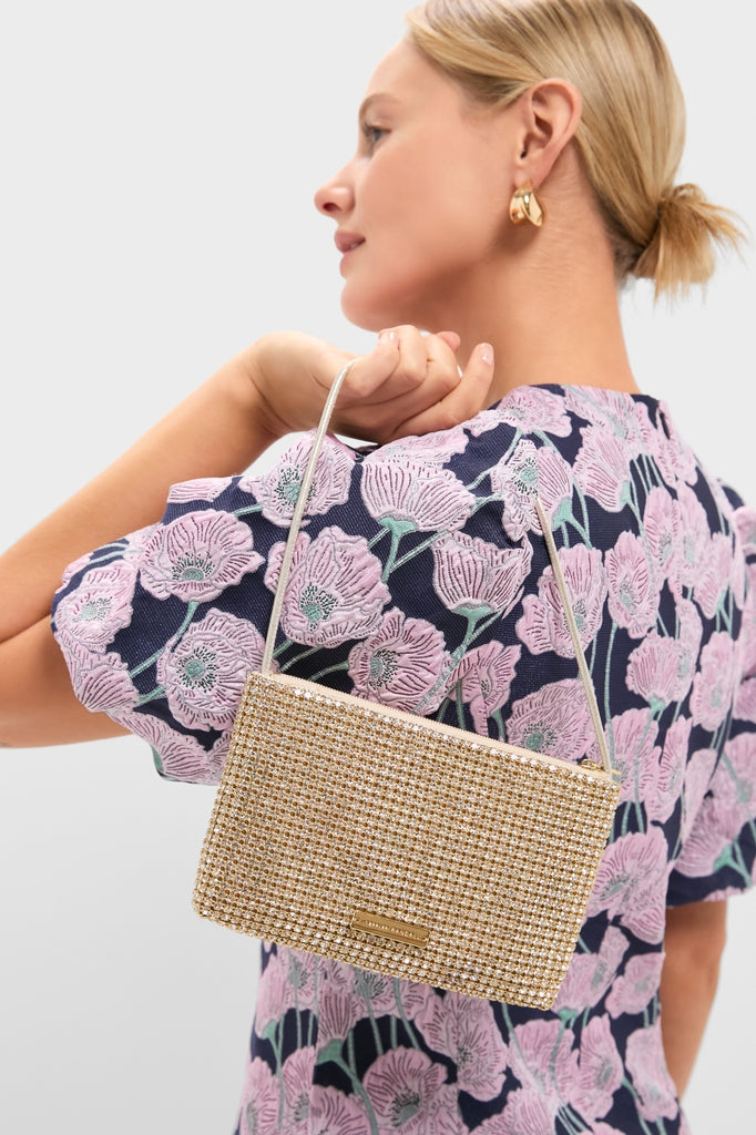 Woman in profile wearing a floral top and gold drop earrings, showcasing the Gold Rhinestone Diamante Clutch—a classic, high-end bag with sparkling crystals and metallic strap. Effortless elegance.