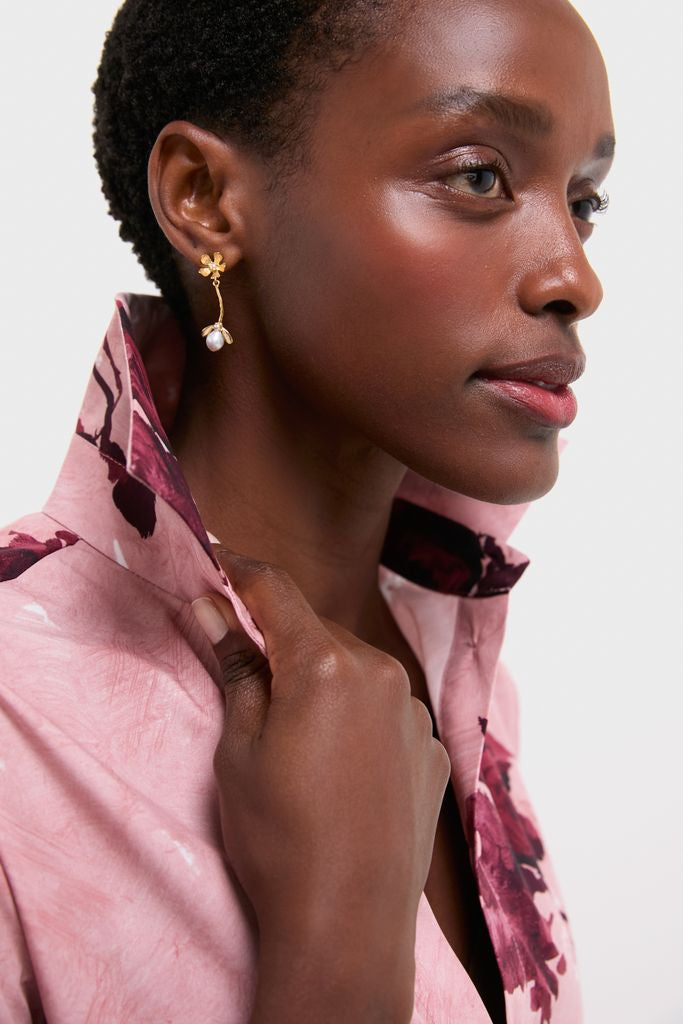 Woman wearing classic Gold Maryanne Earrings, featuring a delicate flower design with a pearl drop, exuding an effortless and high-end style.