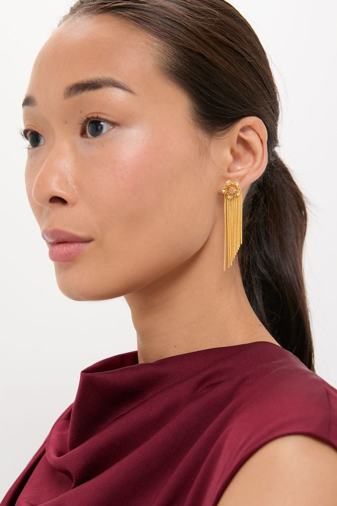 Young woman models Gold Smooth Moves Earrings with cascading fringe and floral motifs; a classic, high-end piece that adds effortless elegance and fun to any outfit.