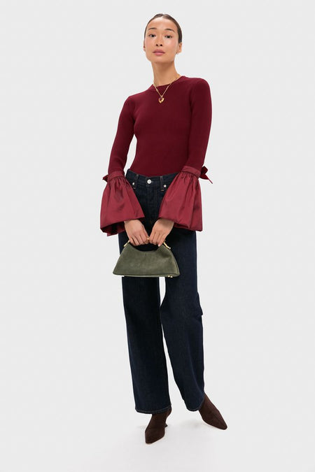 Model wearing the Red Lettie Necklace, paired with an effortlessly classic outfit featuring a dramatic burgundy top, indigo jeans, and a structured olive-green handbag.
