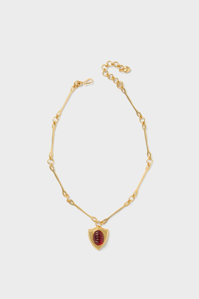 Red Lettie Necklace: A classic gold-tone chain with effortless style, featuring a deep red cabochon shield pendant. Perfect for a fun, high-end look.