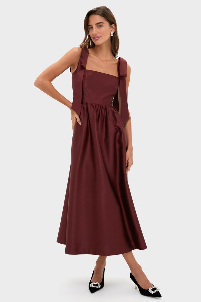 Classic Oxblood Dupioni Bow Esme Dress showcases effortless elegance with its square neckline, wide shoulder bows, and fit-and-flare silhouette, perfect for high-end events.