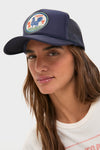 Young woman wears the classic Round Top Trucker Hat featuring a circular Texas rooster patch. This high-end, effortless accessory is perfect for fun, casual outings.