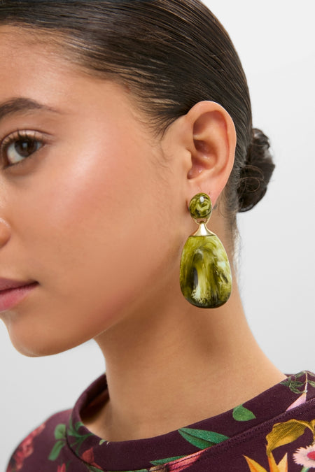 Profile of a woman wearing Malachite River Rock 2 Drop Earrings, featuring green resin stones with brass detailing, exuding a classic, effortless, and high-end style.