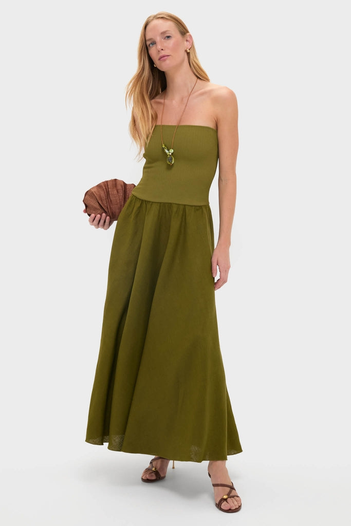 Model in an olive strapless maxi dress, accessorized with the Malachite Brass Rock Cluster Pendant on a leather cord, holding a pleated clutch and exuding classic, effortless elegance.