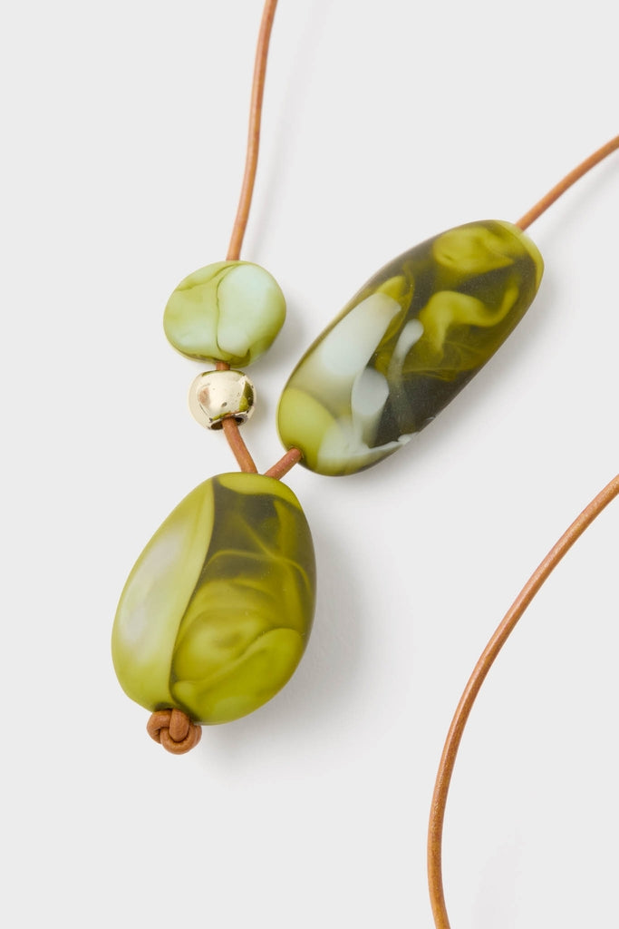 Malachite Brass Rock Cluster Pendant features chunky, marbled green resin beads on a classic leather cord, offering an effortless pop of color for a fun, high-end look.