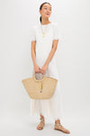 Person in white dress holding tote, showcasing Lemon Brass Rock Cluster Pendant with resin beads on adjustable leather cord; an effortless, high-end accessory for a fun, classic look.