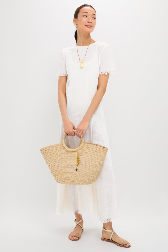 Person in white dress holding tote, showcasing Lemon Brass Rock Cluster Pendant with resin beads on adjustable leather cord; an effortless, high-end accessory for a fun, classic look.