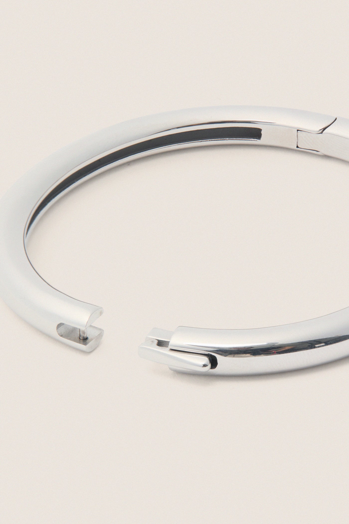Silver Gia Bangle, a classic and high-end bracelet with a polished finish, featuring a hinge and tab lock, effortlessly blends fun and sophistication for a timeless look.