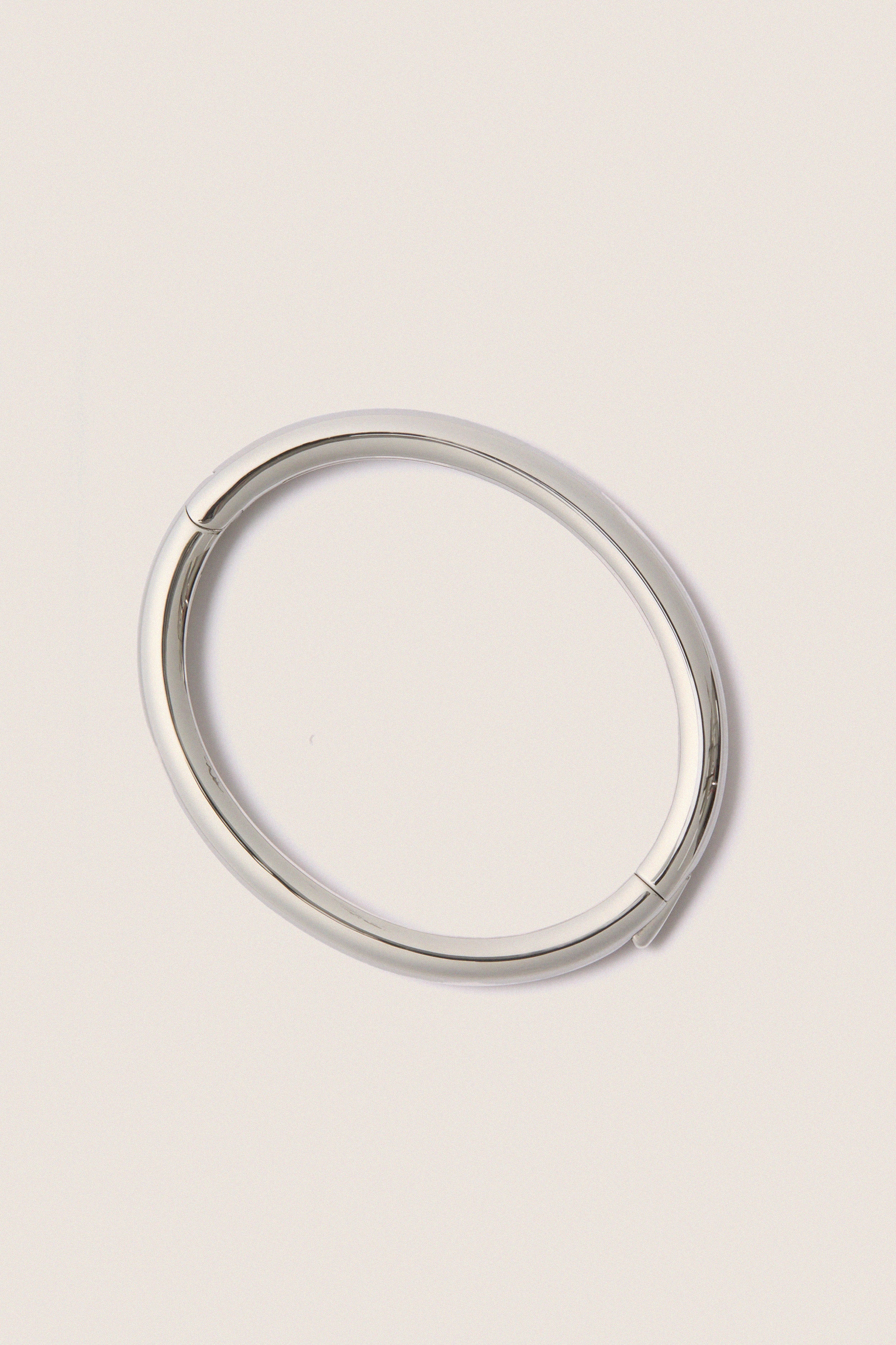 Classic and effortless, the Silver Gia Bangle features a smooth, polished surface with a hinge push closure, embodying a fun, high-end style ideal for any occasion.