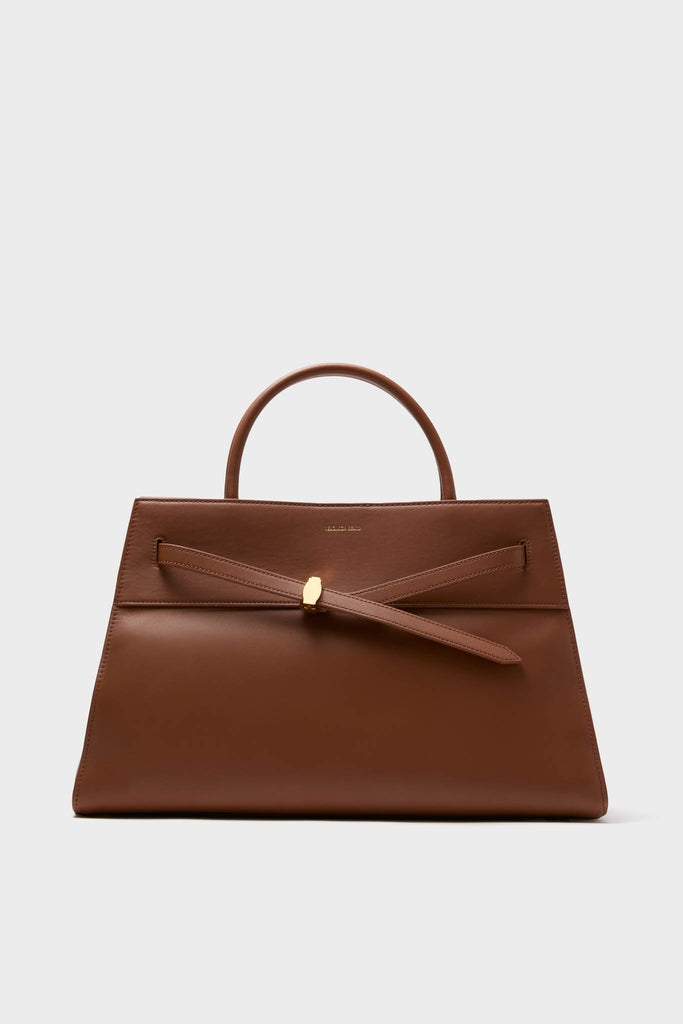 Hazelwood Large Veronica Beard Dash Bag, a classic trapezoidal top-handle handbag in smooth leather, featuring an adjustable knotted strap with gold accent. Effortless and high-end design.